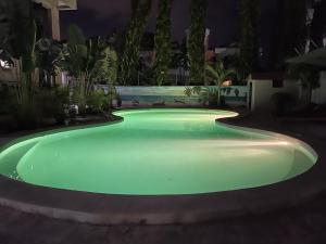 a swimming pool with green lighting in a garden at night at Mudzini gardens - Luxury villa with a pool in Mombasa