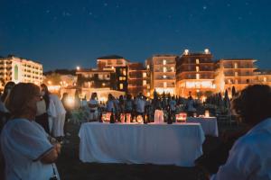 un grupo de personas de pie alrededor de las mesas por la noche en Giovanna Regina Hotel, en Gabicce Mare