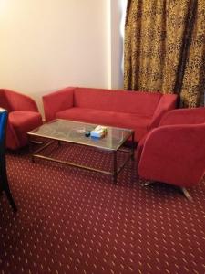 a living room with a red couch and a coffee table at Rawdat Al Safwa Hotel in Medina