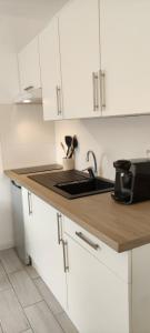 a white kitchen with a sink and a microwave at Charmant studio in Arcachon