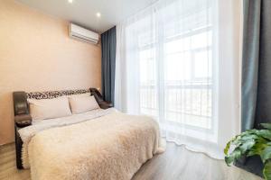 a bedroom with a bed and a large window at Современная студия на Броско с шикарным видом in Khabarovsk