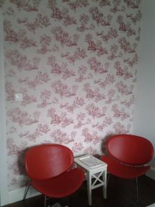 - 2 chaises rouges et une table dans une chambre avec papier peint dans l'établissement La Maison Mirabeau, à Verdun-sur-Meuse