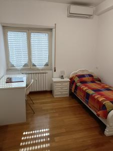 sypialnia z łóżkiem i biurkiem oraz dwoma oknami w obiekcie Gloriapartment w mieście Civitavecchia