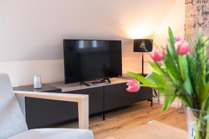 uma sala de estar com uma televisão de ecrã plano sobre uma mesa em Nicolai Suite - Schrangen-Suites-1389 em Lüneburg