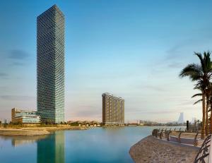 a city skyline with a tall building and palm trees at Shangri-La Jeddah in Jeddah