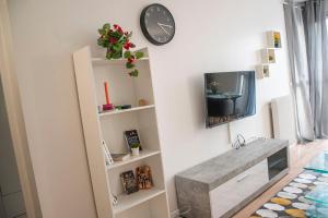 ein Wohnzimmer mit einem TV und einer Uhr an der Wand in der Unterkunft Apartment Villeneuve Stade de France Free parking WiFi in Villeneuve-la-Garenne