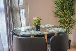 una mesa con tres platos y un jarrón con flores en Apartment Villeneuve Stade de France Free parking WiFi, en Villeneuve-la-Garenne