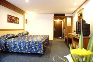 ein Hotelzimmer mit einem Bett und einem Fernseher in der Unterkunft Royal Twins Palace Hotel in Pattaya