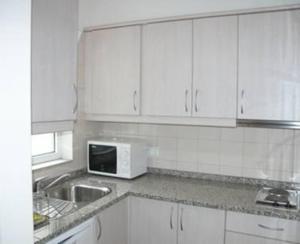 a white kitchen with a sink and a microwave at Villa Pitta in Vila Baleira