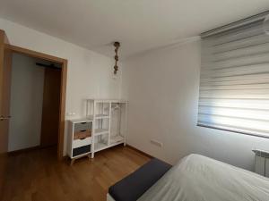 a white bedroom with a bed and a window at El Llano Zaragoza in Zaragoza