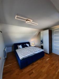 sypialnia z niebieskim łóżkiem w pokoju z drewnianą podłogą w obiekcie Domek Przy Osadzie w mieście Bieliny