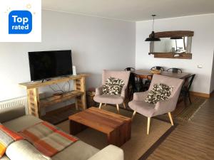 een woonkamer met een bank en stoelen en een televisie bij Depto. orilla de lago Villarrica in Pucón