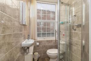 a bathroom with a toilet and a sink and a window at Skegness The Royal Hotel in Skegness