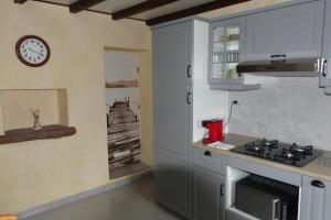 een keuken met een fornuis en een klok aan de muur bij Gîte rural Les Maires d'Avaux in Saint-Bresson