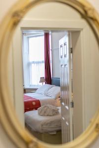 a mirror reflecting a bedroom with two beds and a window at Skegness The Royal Hotel in Skegness