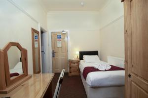 a small bedroom with a bed and a mirror at Skegness The Royal Hotel in Skegness