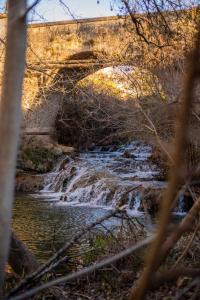 a bridge over a river with a waterfall at Le Vieux Moulin in Jouques