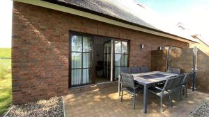 a patio with a table and chairs next to a brick building at Ferienhaus 17 "Gut Tossens" in Butjadingen +2 photos