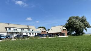 a group of buildings with cars parked in a field at Ferienhaus 17 "Gut Tossens" in Butjadingen
