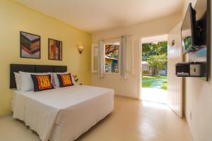 a bedroom with a white bed and a television at Pousada Morada Do Sol in Arraial d'Ajuda