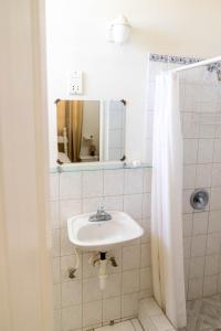 a white bathroom with a sink and a mirror at St. James Guesthouse in Roseau