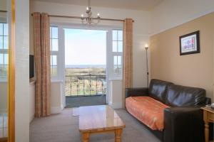 a living room with a leather couch and a window at Skegness The Royal Hotel in Skegness