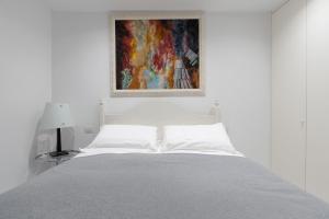 フィレンツェにあるFirenze Rentals - Por Santa Mariaの白いベッドルーム(ベッド1台付)が備わります。壁には絵画が飾られています。