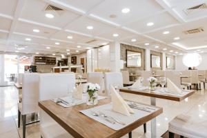 restauracja z drewnianymi stołami i białymi krzesłami w obiekcie Elixír Medical Wellness Hotel w mieście Mórahalom