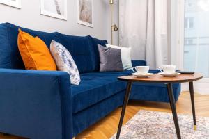 a blue couch with pillows and a table in a living room at Gdynia Śródmieście Żwirki i Wigury by Renters in Gdynia