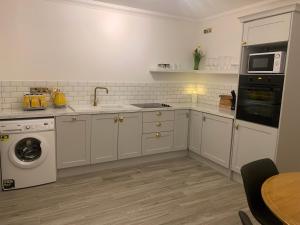 a kitchen with white cabinets and a washer and dryer at Alta House in Westport