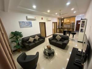 a living room with black couches and a kitchen at Imperial Suites Apartments in Kuching