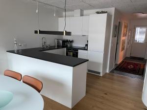 a kitchen with white cabinets and a black counter top at Nice modern apartment in Tórshavn