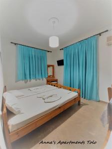 um quarto com uma cama grande e cortinas azuis em Anna's apartments em Tolo