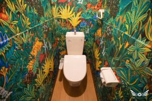 a bathroom with a toilet with a tropical wallpaper at Hakata apartment in Fukuoka