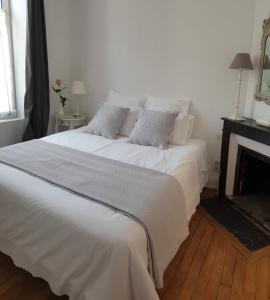 een wit bed in een kamer met een open haard bij La Joséphine in Cosne Cours sur Loire