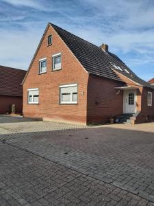 a brick house with white windows and a driveway at Hotel Pension garni Haus am Strand 2 in Norddeich