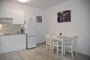 kuchnia z białym stołem i białymi krzesłami w obiekcie Apartament nad fontanną w mieście Rzeszów
