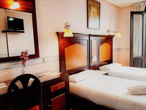 ein Hotelzimmer mit 2 Betten, einem Tisch und einem Schreibtisch in der Unterkunft Hosteria Sara by gaiarooms in Salamanca
