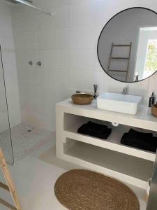 Baño blanco con lavabo y espejo en TAKE TWO lovely beach apartment, Great Brak River, en Groot Brak Rivier