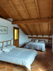 two beds in a room with wooden ceilings at Casa Tartaruga in Trarego