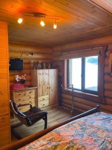 1 dormitorio en una cabaña de madera con cama y escritorio en У Фёдера и Маргариты en Nizhnyaya Grabovnitsa
