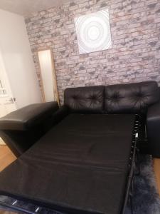 a living room with a couch and a brick wall at Stunning 1 bedroom apartment in Dagenham in Dagenham