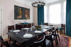 a dining room with a black table and chairs at Impressive 5BR family home in Leafy in London