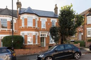 Impressive 5BR family home in Leafy في لندن: سيارة سوداء متوقفة أمام منزل من الطوب