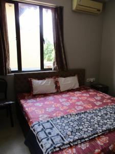 a bed in a room with a window at Ganga Kutir Oak Villa on Raichak in Raichak