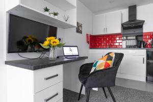 a kitchen with a desk with a television and a chair at Studio Apartments by Lyter Living Desks & Wifi - Monthly Stays Available in Leicester