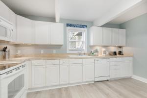 a white kitchen with white cabinets and a window at 118 E ARCTIC UNIT B SALTY SHACK ACROSS THE ST FROM BEACH in Folly Beach +21 photos