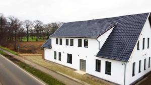 a white house with a black roof on the side of a road at Hochwertige Studios für Monteure I home2share in Stemshorn