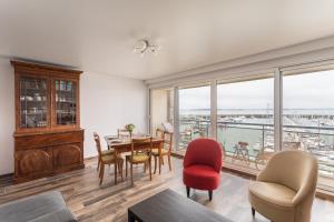 a living room with a table and chairs and a large window at Ty Granny - Superbe vue sur le port in Saint-Cast-le-Guildo