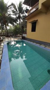 a swimming pool next to a building with palm trees at Alibaug Sunside Villa 3BHK Near Beach in Alibaug